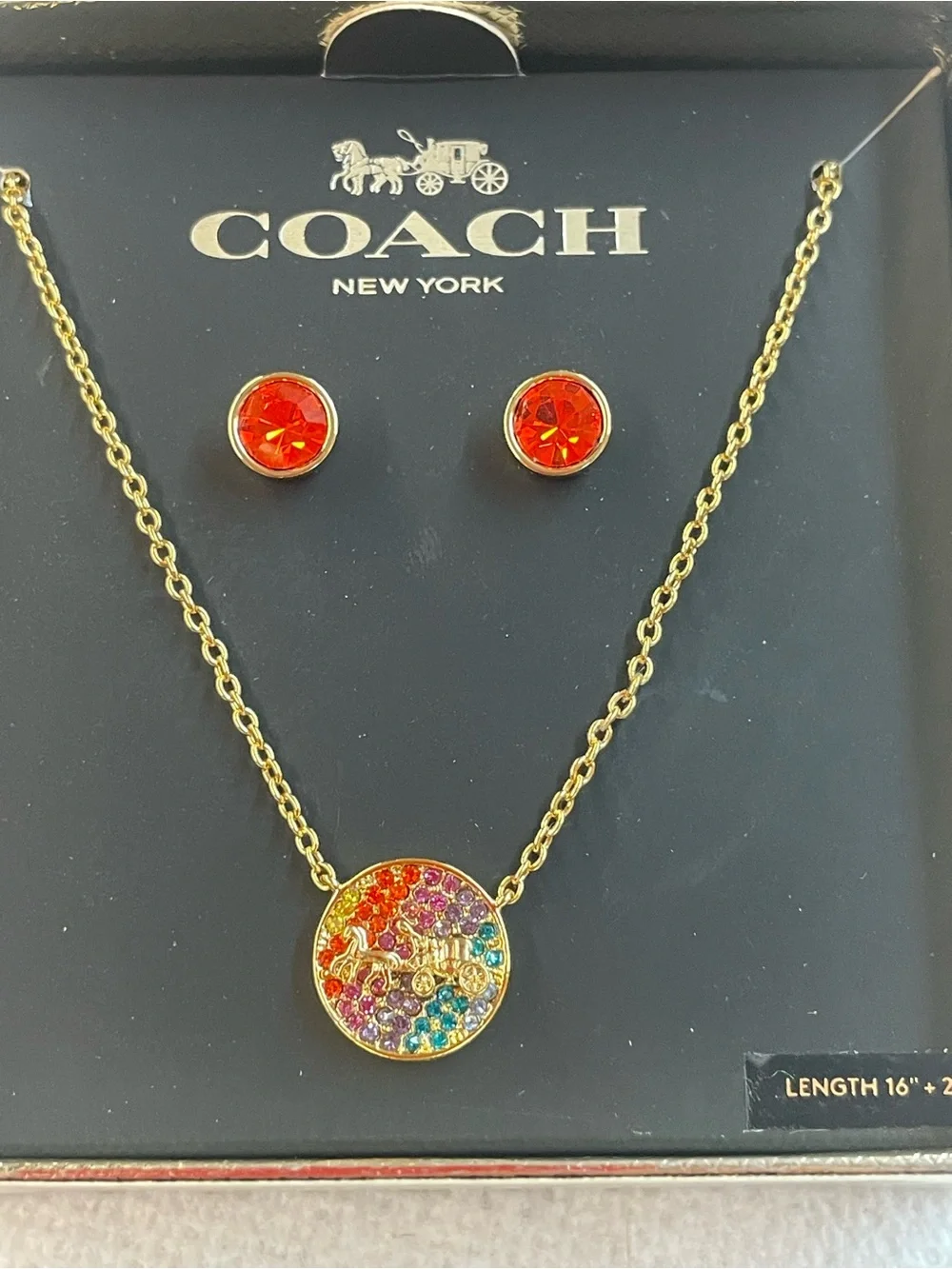 Coach 3-piece jewelry set featuring a gold-tone horse and carriage logo necklace